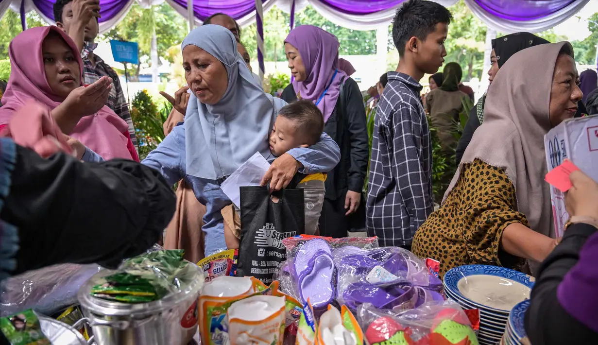 Masyarakat menerima barang-barang gratis seperti pakaian, bahan makanan pokok, dan perlengkapan rumah tangga yang disediakan oleh Asosiasi Organisasi Wanita (GOW) dan pemerintah daerah selama kegiatan aksi sosial tahunan di bulan Ramadan, Surabaya pada Senin 2 Maret 2026. Bersama Pemerintah Kota Surabaya, Jawa Timur, Gabungan Organisasi Wanita (GOW) aksi sosial tahunan, berupa peendistribusian berbagai barang bantuan kepada warga yang membutuhkan. (JUNI KRISWANTO/AFP)