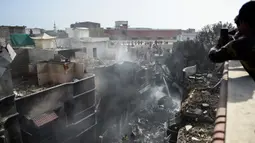 Petugas penyelamat berkumpul di lokasi jatuhnya pesawat Pakistan International Airlines di Karachi, Pakistan, Jumat (22/5/2020). Lokasi kecelakaan berada di perumahan tidak jauh dari Bandara Internasional Jinnah. (Rizwan TABASSUM/AFP)