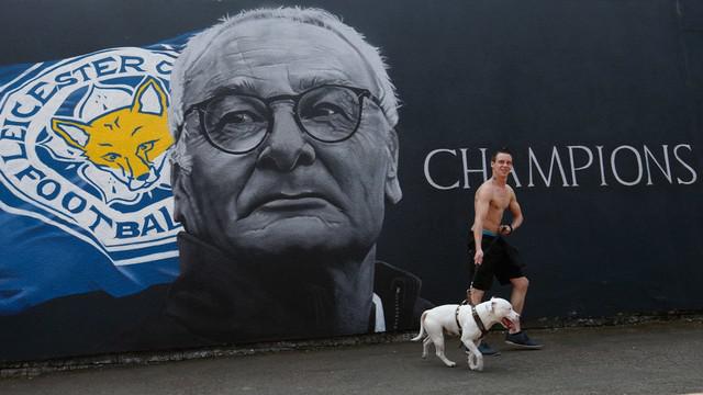 Claudio Ranieri mendapat kejutan dari Christian Fuchs saat sedang memberikan jumpa pers usai Leicester City resmi meraih gelar juara Premier League.