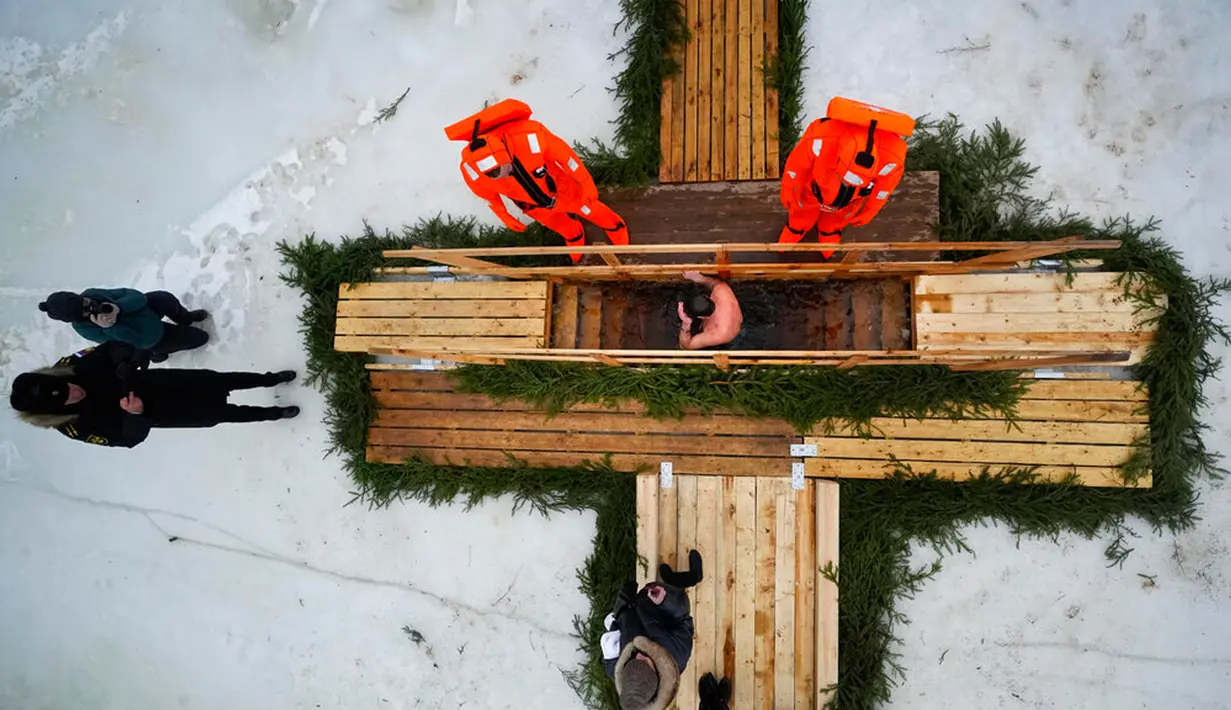 Petugas penyelamat mengamati seorang penganut Ortodoks Rusia yang berendam dalam air es saat perayaan tradisional Epiphany di Kronstadt, luar St. Petersburg, Rusia, 18 Januari 2023. Ribuan pengikut Gereja Ortodoks Rusia terjun ke sungai dan kolam es di seluruh negeri untuk menandai Epiphany, membersihkan diri dengan air yang dianggap suci untuk hari itu. (AP Photo/Dmitri Lovetsky)