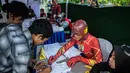 Petugas Kelompok Penyelenggara Pemungutan Suara (KPPS) berkostum superhero The Flash mendata warga yang akan mencoblos dalam Pemilu 2019 di sebuah TPS di Surabaya, Jawa Timur, Rabu (17/4). Ada sembilan petugas KPPS yang mengenakan kostum superhero di TPS ini. (Juni Kriswanto/AFP)