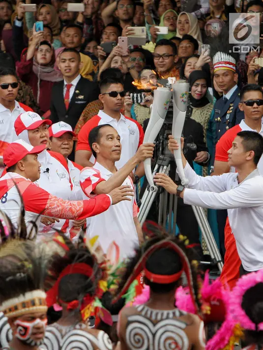 Presiden Joko Widodo saat menyalakan api obor Asian Games 2018 sebelum upacara penurunan Bendera Merah Putih di Istana Negara Jakarta, Jumat (17/8). (Liputan6.com/Pool/Eko)