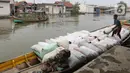 Pekerja mengangkut barang menggunakan perahu menuju dermaga di Desa Pantai Mekar, Muaragembong, Kabupaten Bekasi, Senin (6/12/2021). Jasa angkut barang menggunakan perahu tersebut bertarif Rp 3.000 per 15 kg. (Liputan6.com/Herman Zakharia)