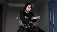 Hijab tersebut pun dipadukan dengan dress hitam sqeuin yang memiliki detail korset keemasan ditambah hiasan rok flowlynya. Nampak lehernya dihiasi kalung menumpuk emas. Credit: Instagram (@nathalieholscher)