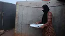 Seorang wanita Suriah menyajikan kotak makanan yang didistribusikan organisasi amal lokal, saat bersiap berbuka puasa selama bulan suci Ramadhan di kamp pengungsi di pinggiran kota Dana yang dikuasai pemberontak, timur perbatasan Turki-Suriah di Idlib (3/4/2022). (AFP/Aaref Watad)