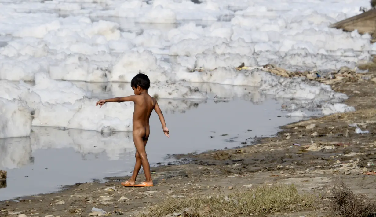Seorang anak bermain di Sungai Yamuna yang tercemar di New Delhi, Sabtu (8/7). Akibat pertumbuhan populasi dan industrialisasi, Yamuna menjadi salah satu sungai paling tercemar di dunia. (DOMINIQUE FAGET / AFP)