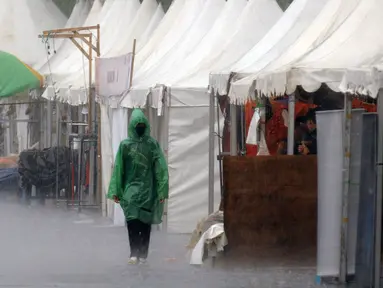 Seorang pengunjung melintas di depan stand produk pakaian pada Festival Kemang yang berlangsung di Jalan Kemang Raya, Jakarta (7/11/2015). Hujan deras disertai angin kencang mewarnai Festival Kemang hari pertama. (Liputan6.com/Helmi Fithriansyah)