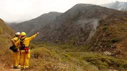 Petugas pemadam kebakaran berjaga-jaga di tebing dekat hutan yang hangus terbakar akibat kebakaran di Garrapata State Park, Big Sur, California, AS, (31/7). Setidaknya 300 telah dievakuasi akibat musibah tersebut. (REUTERS/Michael Fiala)