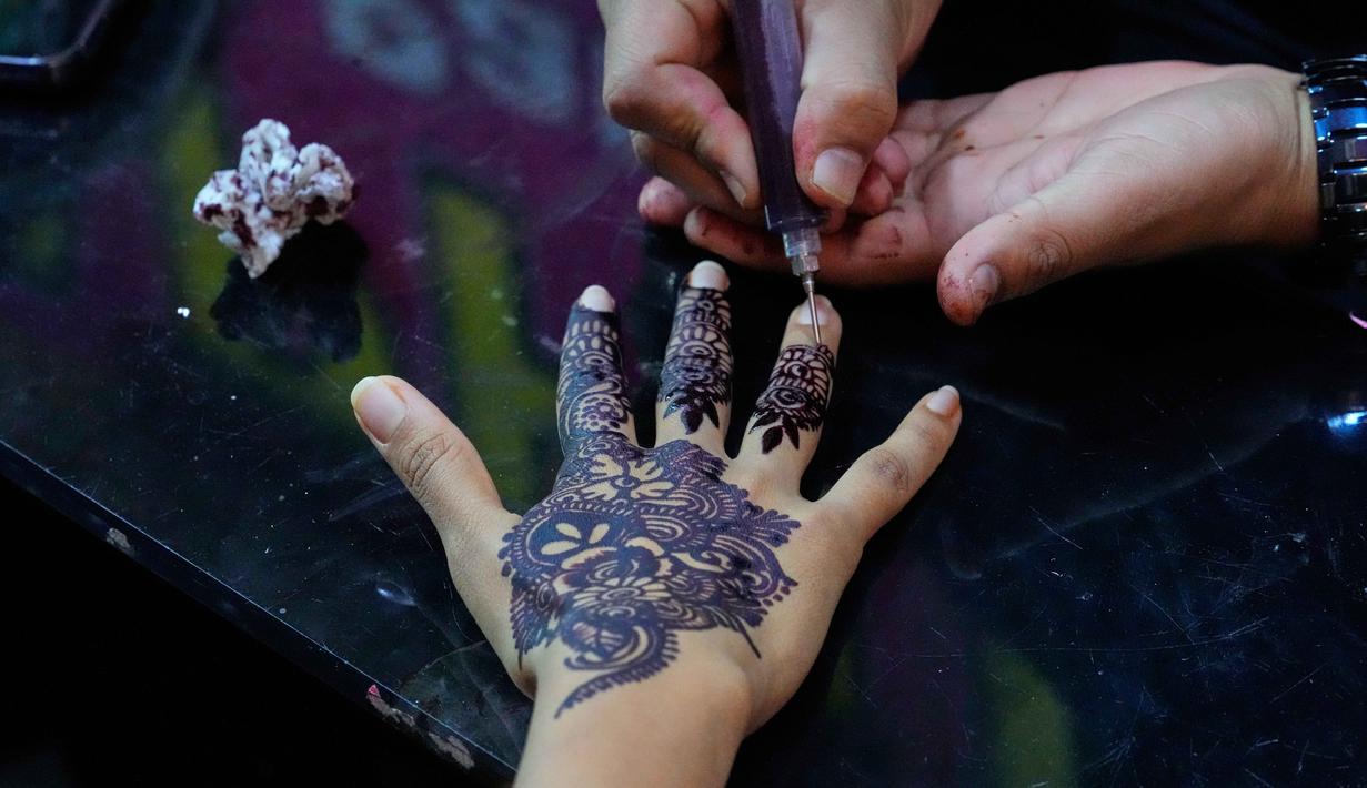 Tradisi ini merupakan simbol kegembiraan dalam menyambut Hari Raya Idul Fitri setelah sebulan berpuasa. Tampak dalam foto, seorang ahli kecantikan melukis 'Henna' tradisional di tangan pelanggan untuk perayaan Idul Fitri, yang menandai berakhirnya bulan suci Ramadan, di Rawalpindi, Pakistan, Rabu, 18 Maret 2026. (AP Photo/Anjum Naveed)