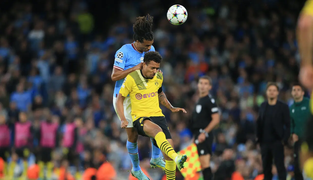 Penyerang Borussia Dortmund Donyell Malen (kanan) berebut bola dengan bek Manchester City Nathan Ake pada laga kedua Grup G Liga Champions di Etihad Stadium, Manchester, Kamis (15/9/2022) dini hari WIB. Menjamu Borussia Dortmund di matchday kedua Liga Champions, Manchester City menang dramatis 2-1 setelah sempat tertinggal lebih dulu. (Photo by Lindsey Parnaby / AFP)
