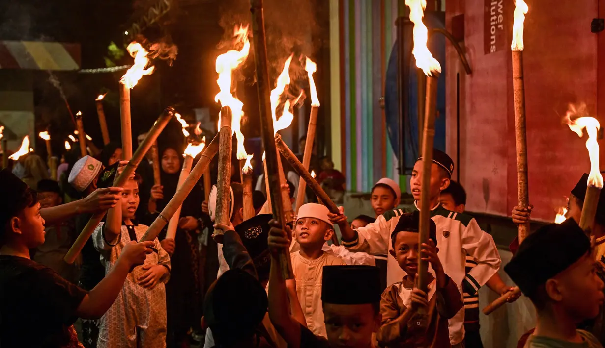 Sejumlah anak-anak mengambil bagian dalam pawai obor pada malam Idul Fitri 1446 Hijriah, yang menandai berakhirnya bulan puasa Ramadan, di Surabaya pada 30 Maret 2025. (JUNI KRISWANTO/AFP)