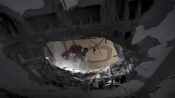 Warga Palestina berusaha memindahkan barang dari salah satu bangunan yang hancur akibat serangan udara militer Israel ke kota Gaza, (12/7/2014). (AFP PHOTO/Mahmud Hams)