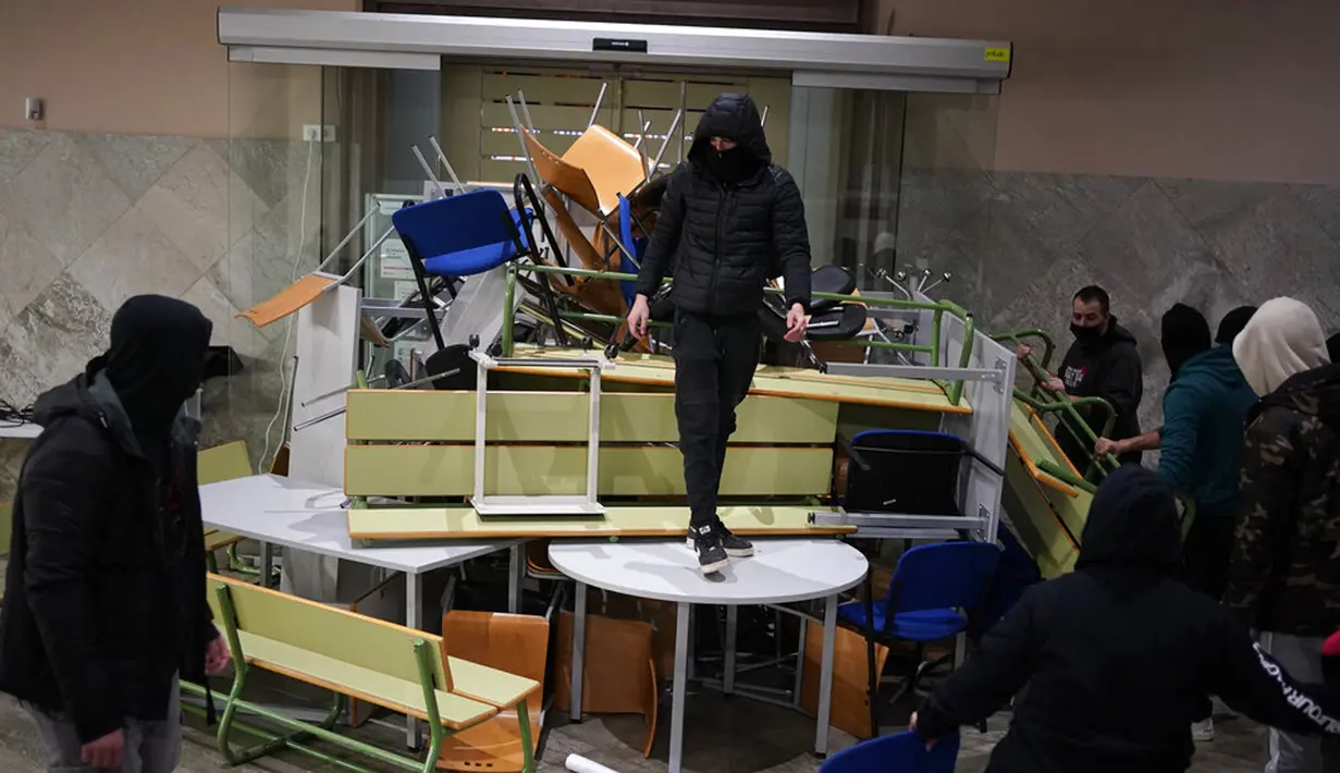 Pendukung rapper Pablo Hasel membuat barikade di dalam Universitas Lleida, Spanyol, Senin (15/2/2021). Pablo Hasel bersama sekitar 20 pendukungnya menggunakan rantai dengan gembok untuk menutup pintu masuk utama ke salah satu gedung Universitas Lleida. (AP Photo/Joan Mateu)