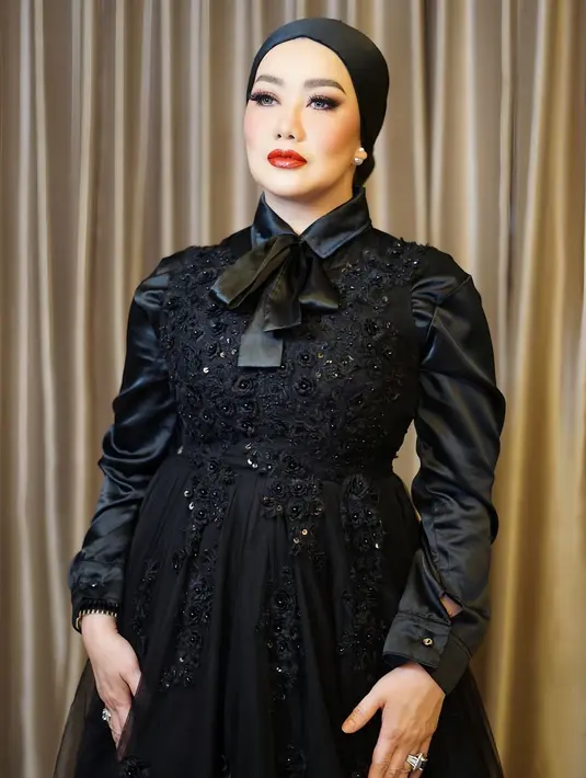 Pesona cantik Reza Artamevia dibalut dress hitam dengan detail berkerah dan pita, serta taburan payet yang menambah kilau pada keseluruhan penampilannya. Reza memadukannya dengan turban hitam dan pulasan riasan bold, serta lipstik merah merona. [Foto: Instagram/rezaartameviaofficial]
