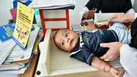 Petugas memeriksa bayi sebelum menyuntikan Vaksin Campak dan Rubella (MR) saat dilakukan imunisasi di sebuah puskesmas, Banda Aceh, Rabu (19/9). Pemprov Aceh akhirnya membolehkan pelaksanaan vaksinasi MR yang mengandung enzim babi (CHAIDEER MAHYUDDIN/AFP)
