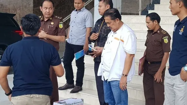 Tersangka korupsi di Riau menunggu mobil tahanan untuk dibawa ke rutan setelah diperiksa jaksa di Kejati Riau.
