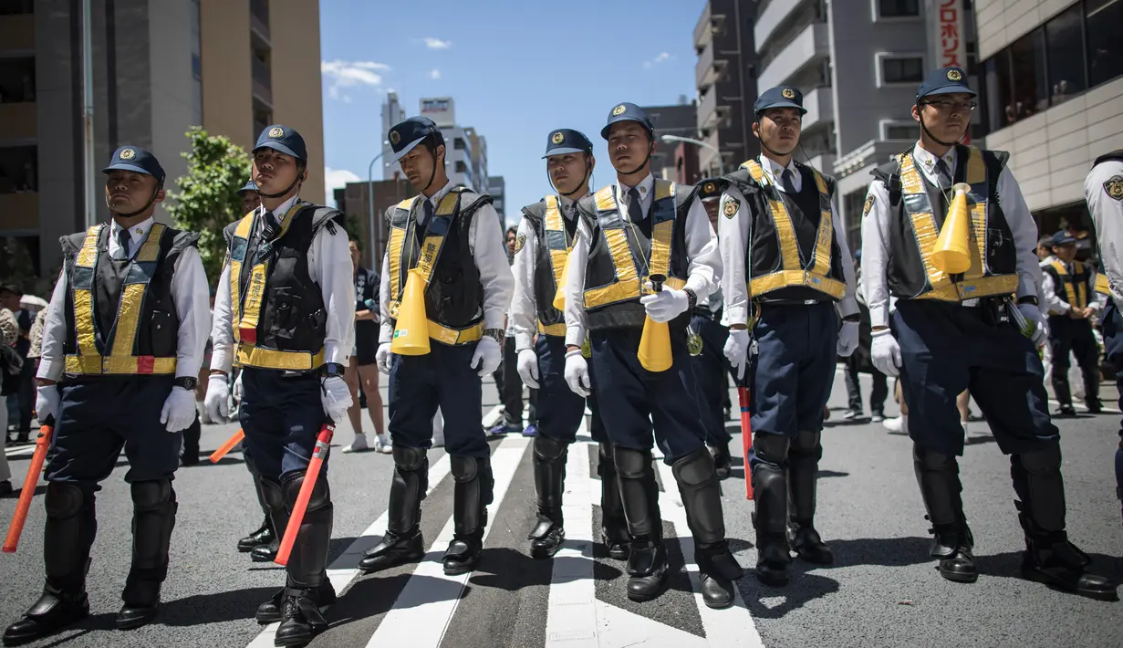 Petugas kepolisian Jepang berjaga selama  Festival Sanja Matsuri di luar kuil Sensoji, distrik Asakusa, Tokyo, Minggu (20/5). Sanja Matsuri adalah festival tahunan di distrik Asakusa yang diadakan pada akhir pekan ketiga pada bulan Mei (AFP/Behrouz MEHRI)