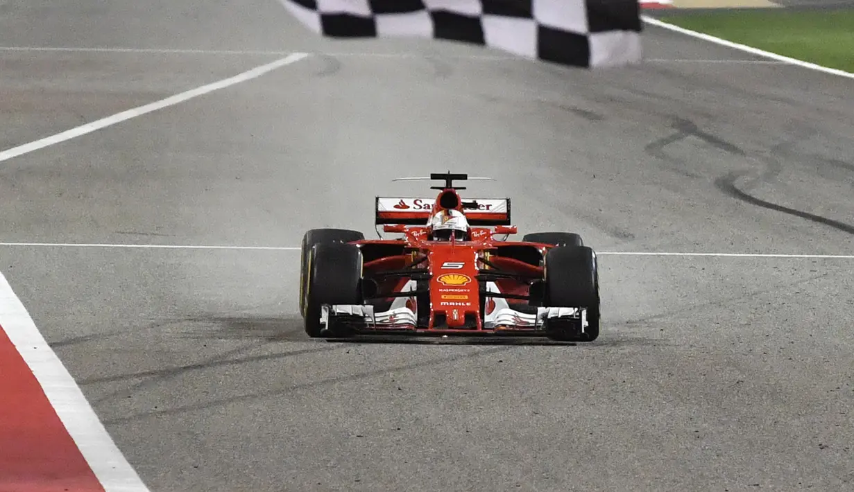 Pebalap Ferrari, Sebastian Vettel saat melintasi garis finish balapan F1 GP Bahrain di Sirkuit Sakhir, Manama, Minggu (16/4/2017).  (AFP/POOL/Andrej Isakovic)