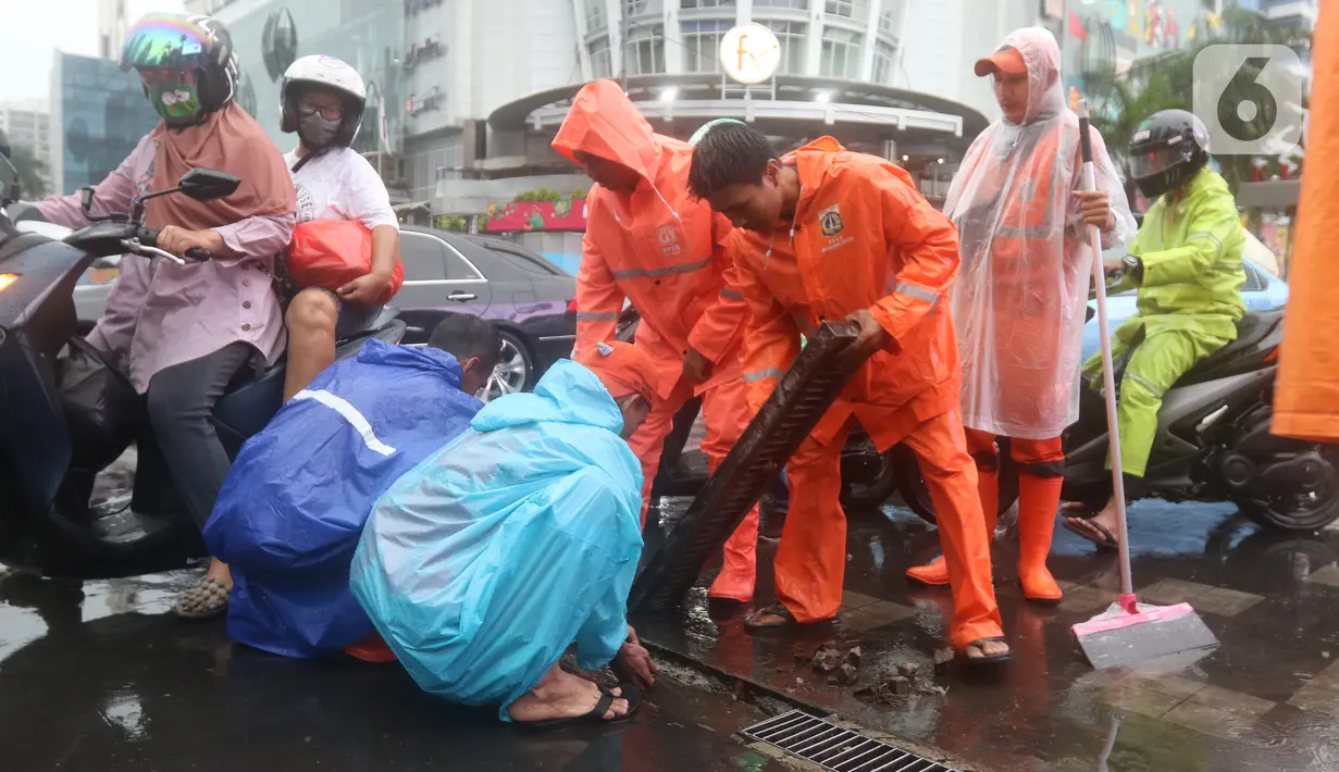 Petugas Penanganan Prasarana dan Sarana Umum (PPSU) membersihkan saluran air di kawasan Gelora Bung Karno, Jakarta, Selasa (17/12/2019). Petugas PPSU membersikan saluran air saat terjadi genangan usai hujan deras mengguyur Jakarta. (Liputan6.com/Herman Zakharia)