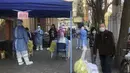 Petugas medis melakukan tes massal untuk warga di area lockdown di distrik Jingan, Shanghai barat (4/4/2022). China telah mengirim lebih dari 10.000 petugas kesehatan dari seluruh negeri ke Shanghai, termasuk 2.000 staf medis militer. (AP Photo/Chen Si)