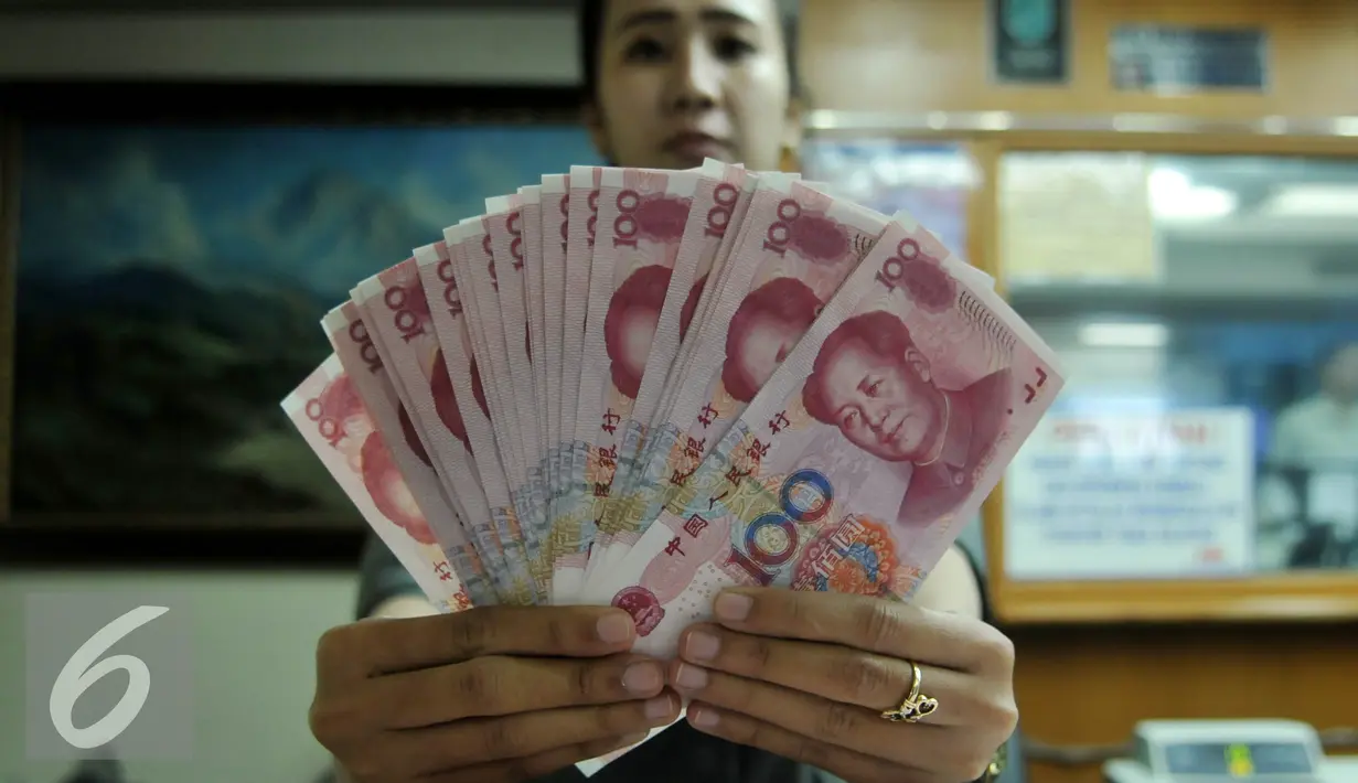 Petugas menunjukkan uang pecahan 100 Yuan di tempat penukaran uang, Jakarta, Kamis (13/8/2015). Kebijakan Tiongkok yang sengaja melemahkan (devaluasi) mata uang Yuan membuat Rupiah melemah terhadap dolar AS. (Liputan6.com/Johan Tallo)