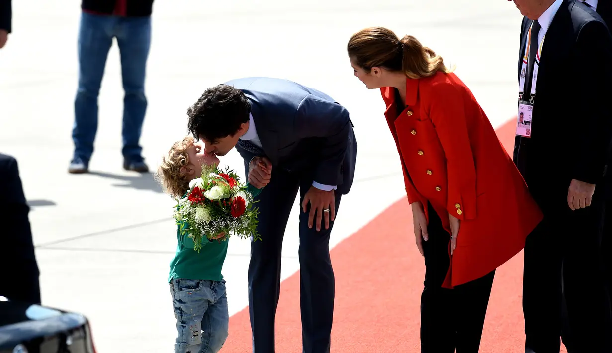 PM Kanada Justin Trudeau mencium sang putra, Hadrien, saat setibanya di Hamburg, Jerman, Kamis (6/7). PM Kanada membawa istri, Sophie Gregoire-Trudeau, dan putranya untuk menghadiri KTT G20. (PATRIK STOLLARZ / AFP)