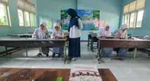 Seorang guru memberikan pelajaran matematika kepada empat murid baru kelas X di SMA 1 Muhammadiyah Depok,  Jawa Barat, Selasa (22/7/2025). (merdeka.com/Arie Basuki)