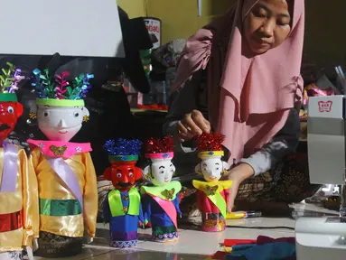 Perajin menyelesaikan pembuatan miniatur ondel-ondel di rumah produksi Kramat Jati, Jakarta, Senin (23/6/2019). Miniatur ondel-ondel yang terbuat dari limbah botol plastik itu dibuat sesuai dengan pesanan. (merdeka.com/Arie Basuki)