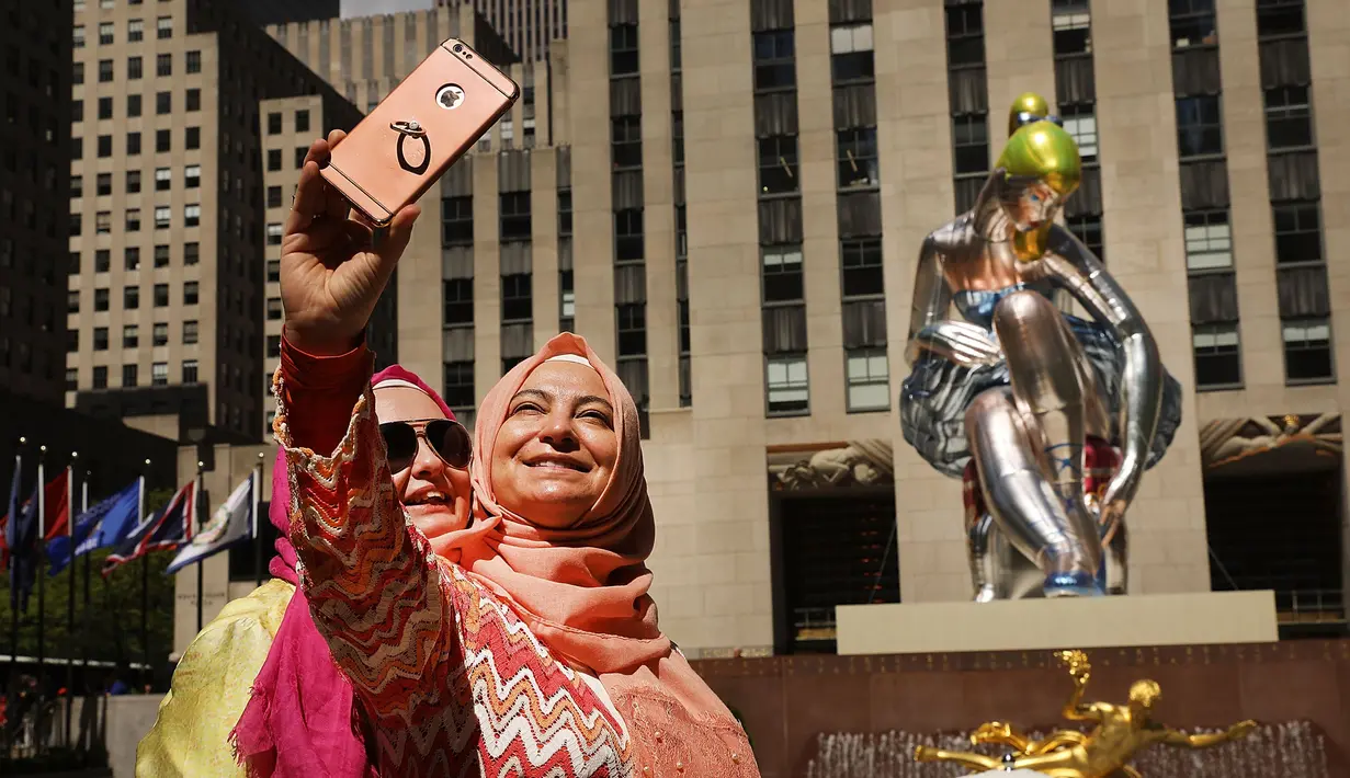 Dua orang wanita berswafoto di dekat balon penari balet karya seniman Jeff Koons, di Rockefeller Center, New York City, AS, Jumat (12/5). Keberadaan balon penari balet menjadi ajang foto pengunjung Rockefeller Center. (Spencer Platt / Getty Images / AFP)