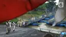 Pejalan kaki berjalan melintasi jembatan perahu di atas Sungai Citarum, Karawang, Jawa Barat, Sabtu (20/11/2021). Jembatan perahu ini menjadi jalan alternatif yang menghubungkan antara Desa Anggadita dengan Kawasan Pabrik Dusun Rumambe 1. (merdeka.com/Imam Buhori)