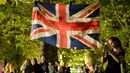 <p>Seorang wanita mengambil foto lambang bendera Inggris saat orang-orang memberikan penghormatan bunga kepada Ratu Elizabeth II di Green Park London, Senin, (12/6/2022). Bukan hanya itu, Ratu Inggris ini juga menjadi pimpinan semua cabang militer Inggris dan menjadi pendukung keuangan atas lebih dari 700 organisasi di seluruh dunia. (AP Photo/Vadim Ghirda)</p>