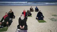 Sejumlah wanita Palestina berlatih yoga di pantai di Gaza City (3/3/2020). Pelatihan yoga tersebut diselenggarakan oleh Positive Energy Club. (AFP Photo/Mohammed Abed)