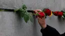 Seorang pria meletakkan bunga mawar di tembok selama peringatan runtuhnya Tembok Berlin, di bekas jalur perbatasan antara Berlin Timur dan Berlin Barat, di Bernauer Strasse, pada tanggal 9 November 2023. (Odd ANDERSEN/AFP)