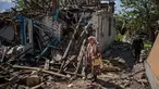 Sepasang penduduk membawa barang bawaan dari rumah mereka yang hancur di tengah invasi Rusia ke Ukraina, di desa Vilkhivka, dekat kota timur Kharkiv, pada 14 Mei 2022. Puluhan rumah di Vilkhivka, sebuah desa berpenduduk sekitar 2.000 jiwa, hancur oleh peluru, ledakan atau kebakaran. Puing-puing berserakan di jalan-jalan termasuk selongsong peluru, dan sisa-sisa amunisi. (Dimitar DILKOFF / AFP)