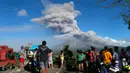 Warga menyaksikan gumpalan asap tebal yang keluar dari puncak Gunung Mayon di Kota Legazpi, Provinsi Albay, Filipina, Selasa (23/1). (AP Photo/Bullit Marquez)