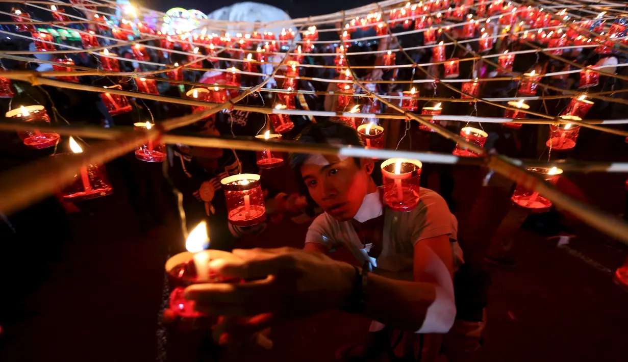 Warga menyalakan lilin sebelum melepaskan lampion buatan tradisional ke langit selama festival tahunan Tazaungdaing di Taunggyi, Myanmar (19/11). (REUTERS/Soe Zeya Tun)