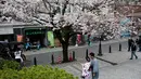 Pengunjung berpose di dekat Bunga Sakura di kawasan Asakusa Tokyo, Kamis (6/4). Memasuki bulan April, bunga Sakura mulai bermekaran dan menggoda mata untuk melihatnya.  (AFP Photo/ Behrouz MEHRI)