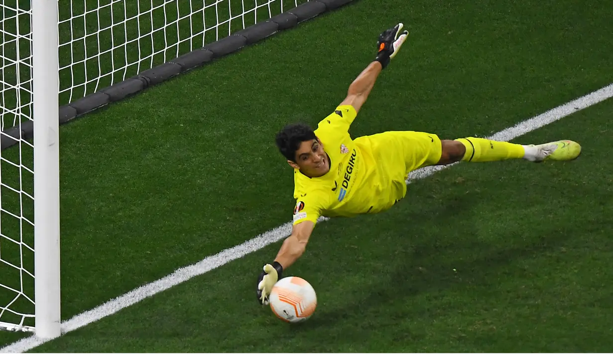 Eskpresi kiper Sevilla, Yassine Bounou, saat menggagalkan tendangan penalti pemain AS Roma, Roger Ibanez, dalam babak adu penalti final Liga Europa 2022/2023 yang berlangsung di Stadion Puskas Arena, Hungaria, Jumat (01/06/2023) dini hari WIB. (AFP/Ferenc Isza)