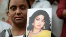 Seorang wanita memegang foto aktris Bollywood Sridevi Kapoor saat berdiri di luar rumah sang idola jelang pemakamannya, Mumbai, India, Rabu (28/2). (PUNIT PARANJPE/AFP)