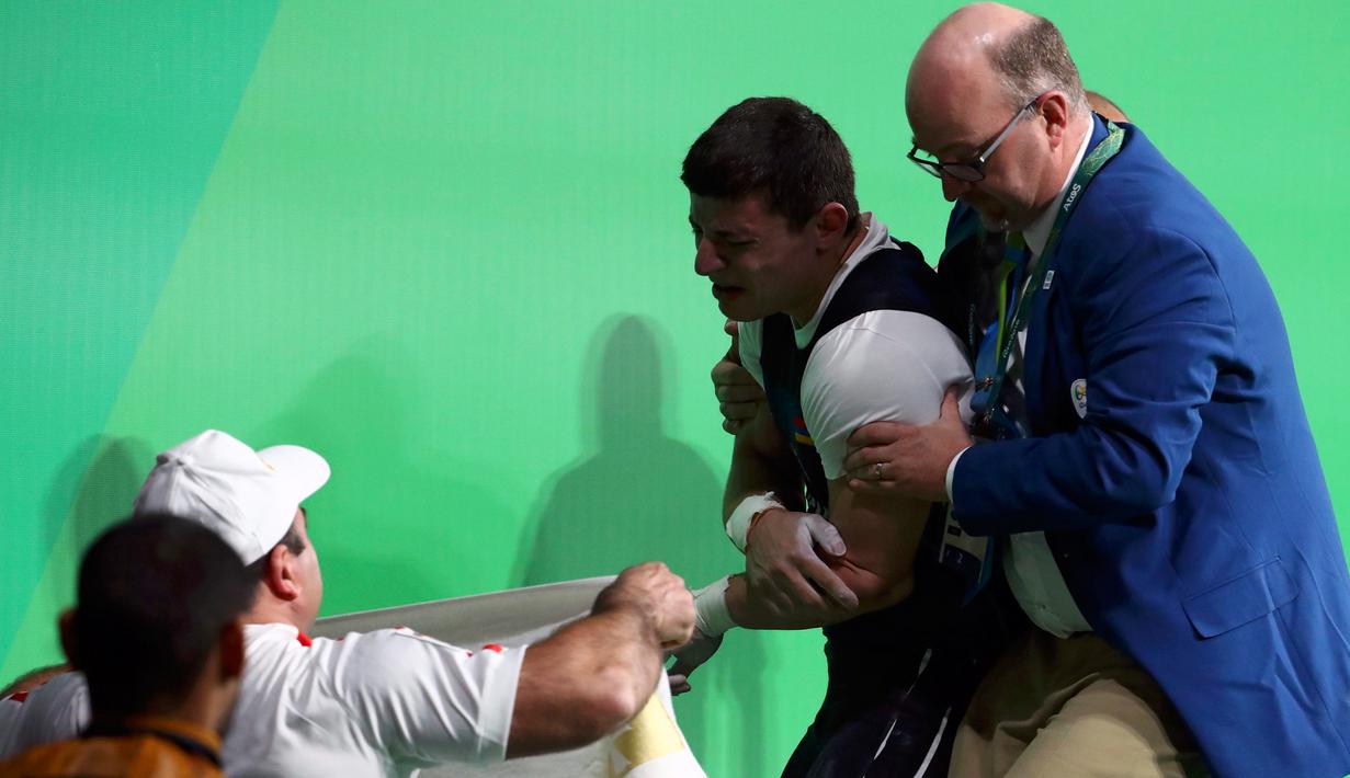 Atlet angkat besi Armenia, Andranik Karapetyan menahan sakit dan menangis usai mengalami cedera horor ketika tampil pada Olimpiade 2016 di Rio de Janeiro, Rabu (10/8). Siku Karapetyan patah saat hendak mengangkat beban 195 kilogram (REUTERS/Yves Herman)