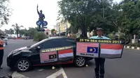 Pria Solo berkeliling kota sambil menempelkan bendera Malaysia terbalik bersanding dengan Bendera Merah Putih. (Liputan6.com/Fajar Abrori)