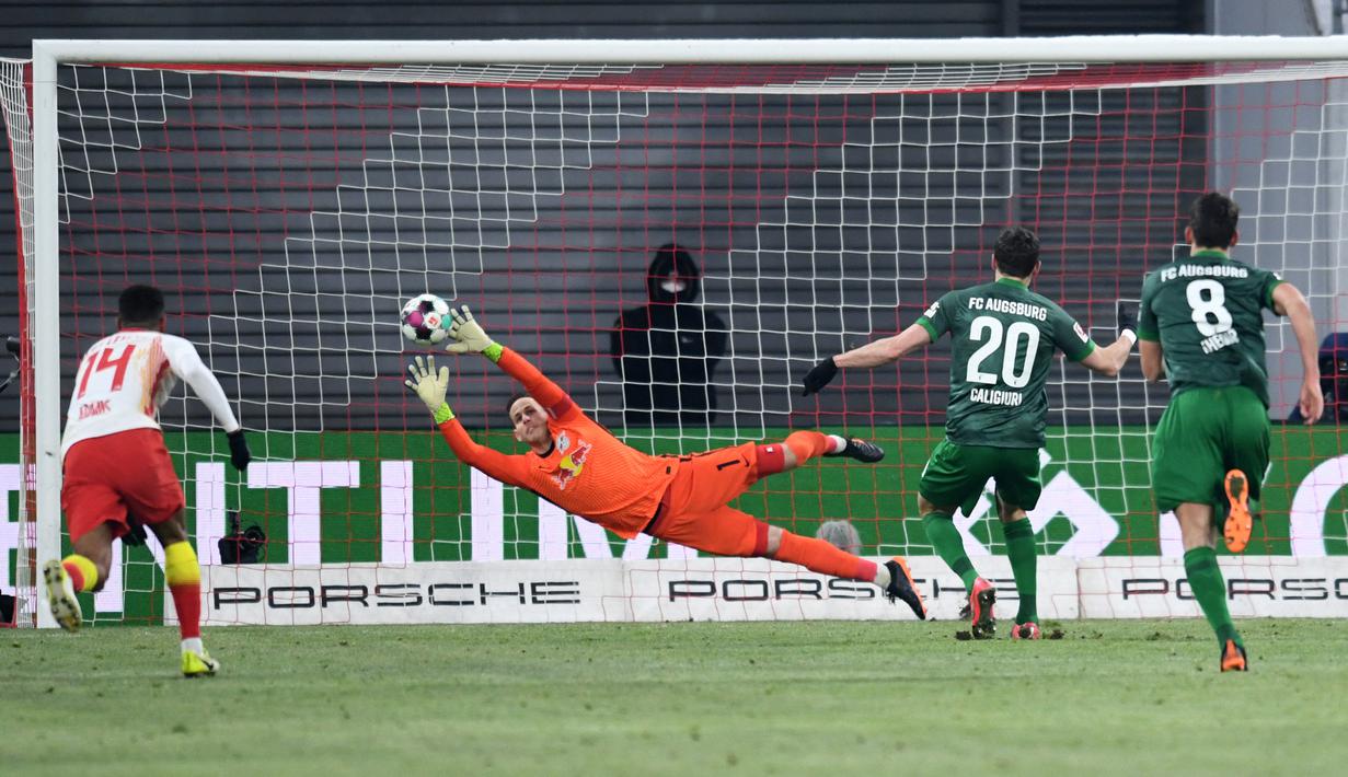 Aksi ciamik juga ditunjukkan oleh kiper RB Leipzig, Peter Gulacsi tapi sayangnya bola tendangan dari pemain Augsburg Daniel Caligiuri tidak bisa dibendung olehnya. (Foto: AFP/Pool/Annegret Hilse)