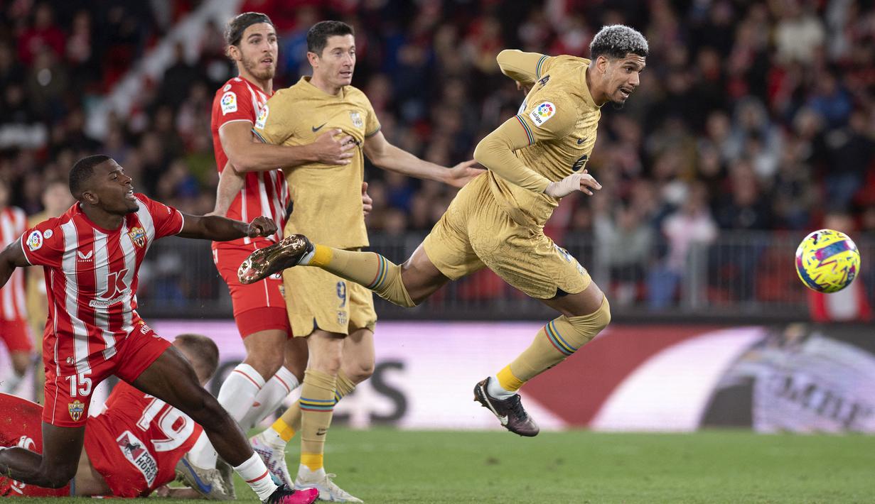 Pemain Barcelona, Ronald Araujo berusaha melewati pemain Almeria pada laga lanjutan Liga Spanyol 2022/2023 yang berlangsung di Power House Stadium, Senin (27/02/2023) dini hari WIB. (AFP/Jorge Guerrero)
