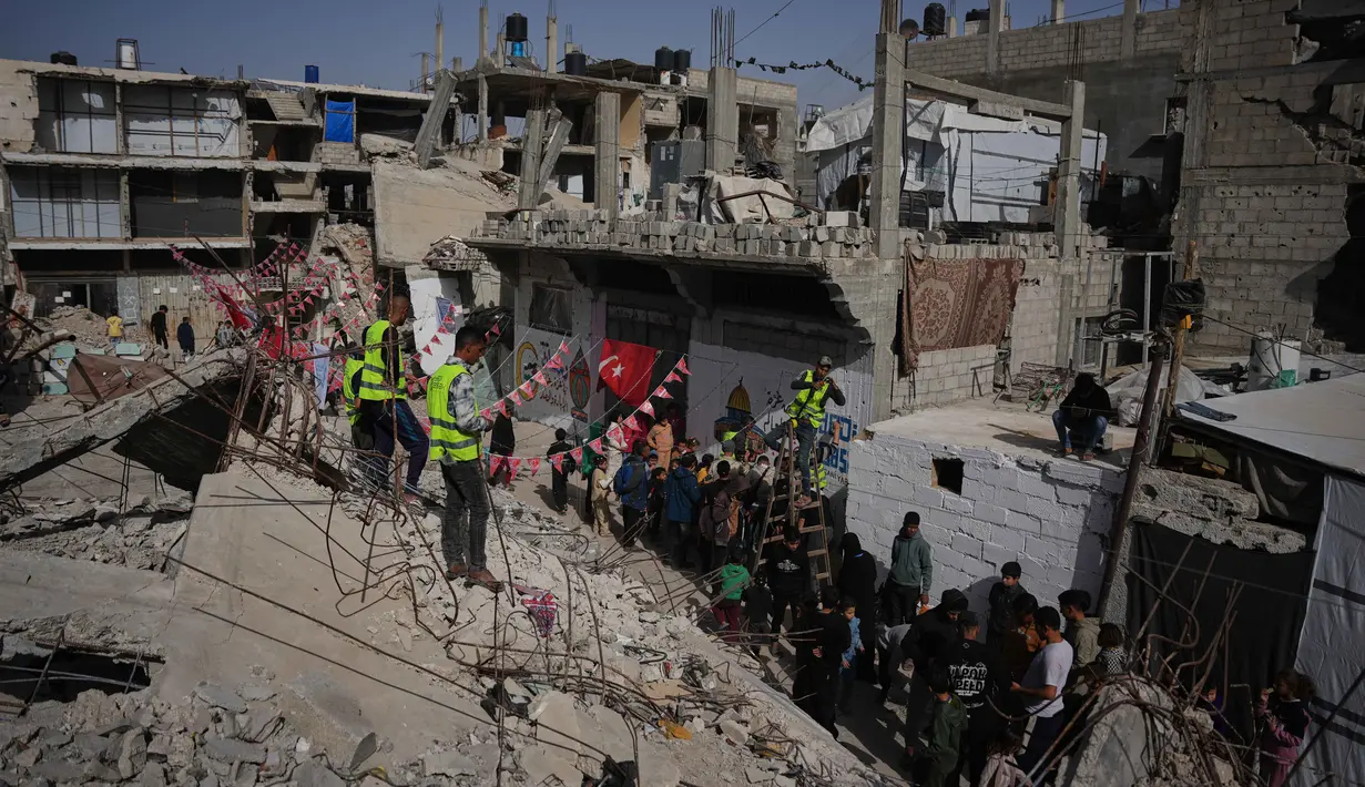 Reruntuhan bangunan berhias ucapan serta pesan Selamat Datang Ramadan yang menjadi simbol ketahanan warga Palestina di Gaza. Tampak dalam foto, warga Palestina menggantungkan hiasan Ramadan di samping reruntuhan rumah yang hancur di Khan Younis, Jalur Gaza selatan, Minggu 15 Februari 2026. (AP Photo/Abdel Kareem Hana)