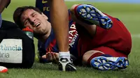 Barcelona's Lionel Messi grimaces as he lies on the pitch after injuring his left knee during their Spanish first division soccer match against Las Palmas at Camp Nou stadium in Barcelona, Spain, September 26, 2015. REUTERS/Sergio Perez