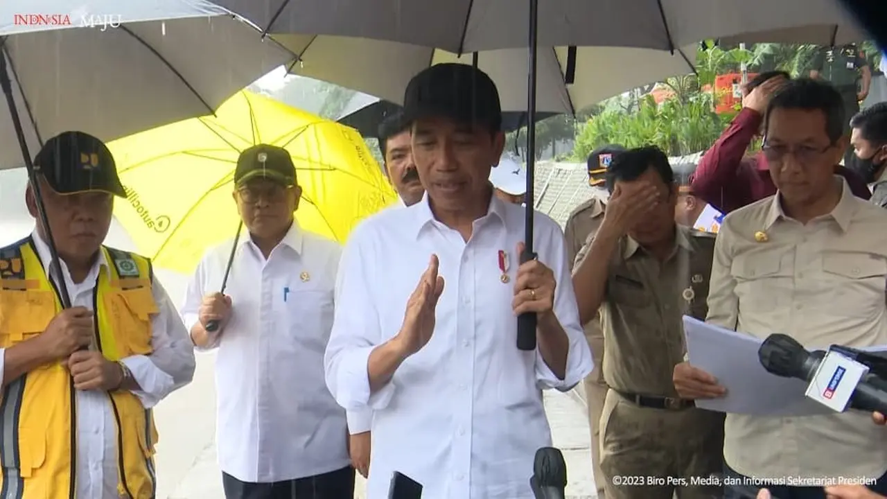 Presiden Joko Widodo atau Jokowi meninjau normalisasi Kali Ciliwung di Jakarta, ditengah guyuran hujan, Selasa (21/2/2023)