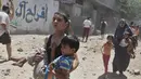 Pemuda Palestina menggendong adiknya berlari mencari tempat aman saat terjadi serangan udara Israel di Gaza, Rabu (9/7/14). (REUTERS/Majdi Fathi)