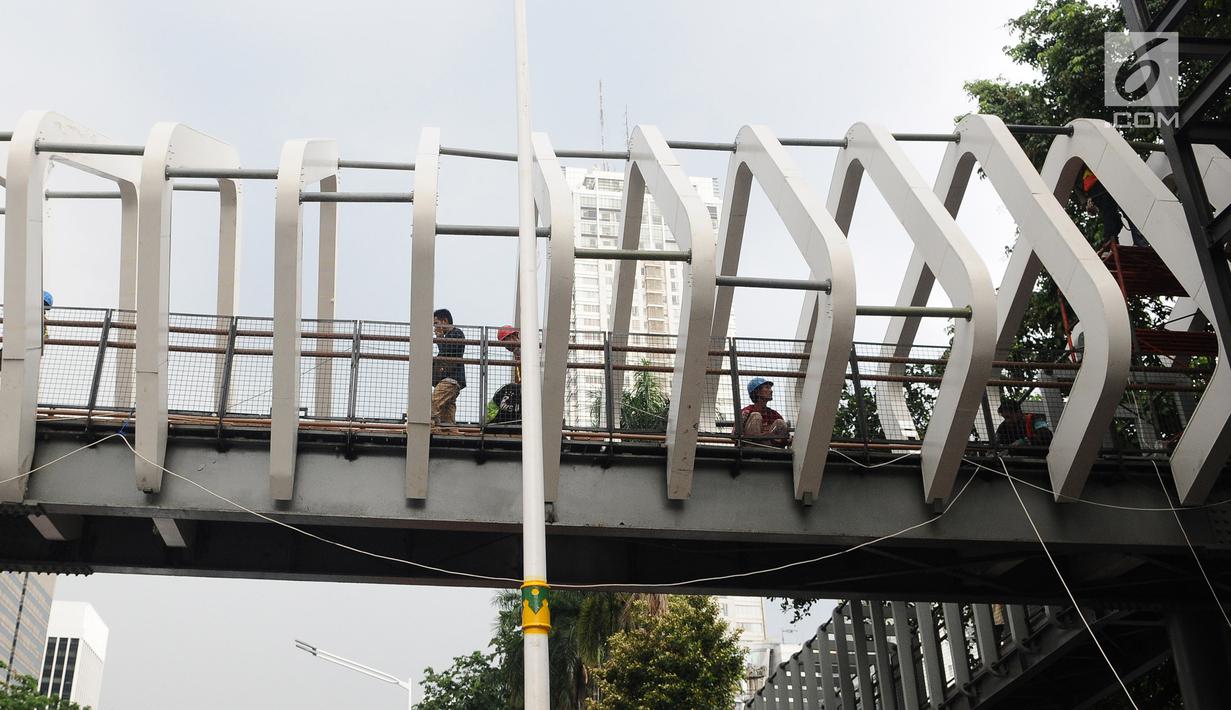 Petugas menyelesaikan proyek pembangunan jembatan penyeberangan orang (JPO) Gelora Bung Karno di kawasan Sudirman, Jakarta, Sabtu (5/1). Revitalisasi tiga di kawasan Sudirman ditargetkan selesai pada pertengahan Januari 2019 (Liputan6.com/Herman Zakharia)