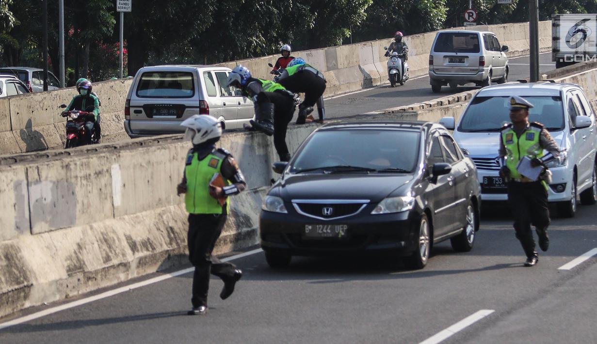 Petugas polisi lalu lintas (polantas) mengejar pengendara sepeda motor  yang melintasi JLNT Kampung Melayu-Tanah Abang, Jakarta, Selasa (25/7). Sepeda motor dilarang melintas di JLNT tersebut karena merupakan jalur cepat. (Liputan6.com/Faizal Fanani)