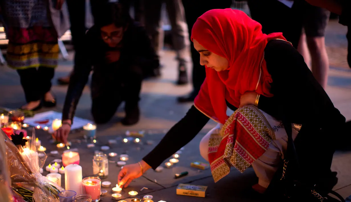 Seorang wanita menyalakan lilin sehari setelah serangan bunuh diri di sebuah konser Ariana Grande di Albert Square, Manchester, Inggris, (23/5). (AP Photo/Emilio Morenatti)